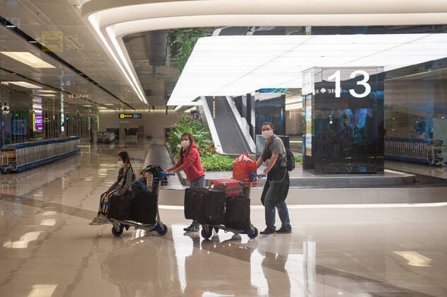 31.01.2020, Singapur, Republik Singapur, Asien - Flugreisende kommen am Flughafen Changi an und tragen Atemschutzmasken, um sich vor einer Ansteckung mit dem Coronavirus zu schuetzen.