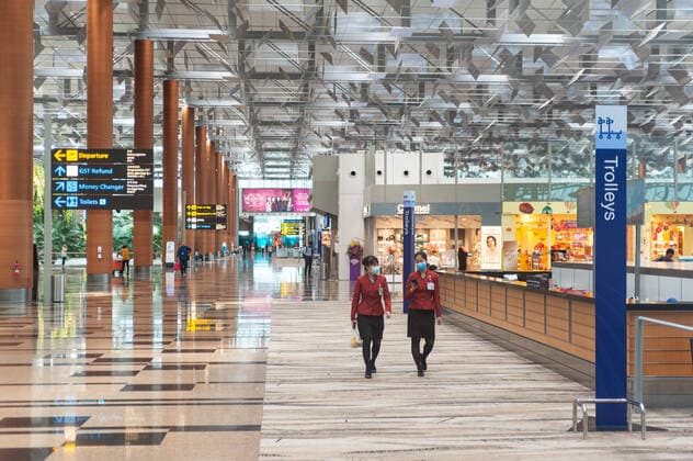 31.01.2020, Singapur, Republik Singapur, Asien - Zwei Flughafenangestellte tragen Atemschutzmasken waehrend sie durch die Abflughalle des Terminal 3 am Flughafen Changi gehen.