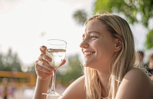 lachende junge Frau trinkt Wein