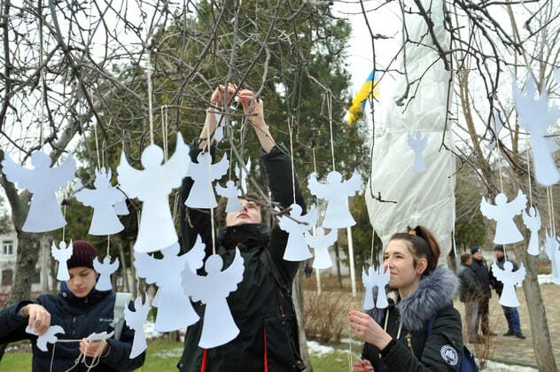 SIEVIERODONETSK, LUHANSK REGION, UKRAINE - FEBRUARY 20, 2020 - Woman hangs a paper angel onto a branch of a tree during the Angels of Memory action in Sievierodonietsk, eastern Ukraine. Angels of Memory action held in Sieverodonietsk  Copyright: xOleksiixKovaliovx