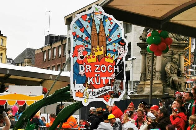 Schild D’r Zock kütt (Der Zug Kommt) am Anfang des Rosenmontagszug in Köln mit feiernden Menschen am Straßenrand Rosenmontagszug in Köln 2020, 24.02.20 Köln NRW Deutschland Alter Markt