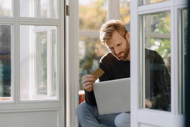 Man using laptop and credit card in sunroom at home model released Symbolfoto property released  KNSF07087
