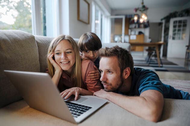 Happy family lying on couch, using laptop model released Symbolfoto property released  KNSF07268