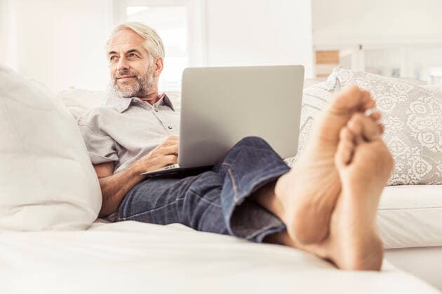 Mature man using laptop on couch at home model released Symbolfoto property released  SDAHF00328