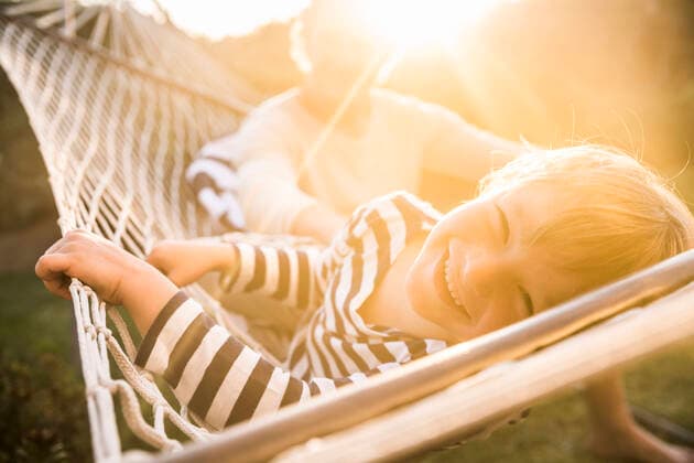 Creative Highlights Symbolfotos Portrait of smiling boy lying in hammock with father in background model released Symbolfoto  SDAHF00367