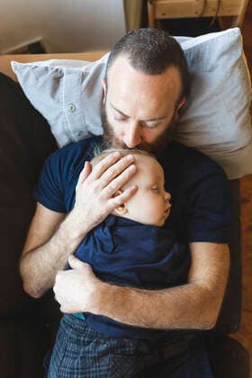 Father kissing his sleeping son on the sofa model released Symbolfoto  WPEF02489