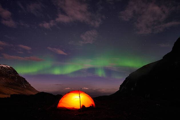 Nordlicht (Auroa borealis) ueber erleuchtetem Zelt, Norrbotten, Lappland, Schweden, Oktober 2014 McPGUN
