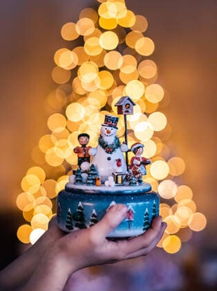 Close up of hands holding snowman music box with lights in background Kingston, ON, Canada ,model released, Symbolfoto CR_DOHO200115B-281174-01