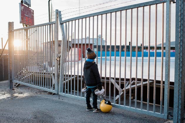 IMAGO Creative: NGO, Ausbildung für Kinder boy holding skates looking through a fence at an empty ice rink NorrtoÂ¤lje, Stockholm County, Sweden ,model released, Symbolfoto CR_RABE200115-269082-01