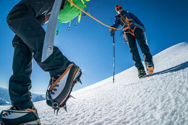 A female mountaineer in cramp-ons leads the way down a glacier. United States, Washington, Coleman Deming Route Mt. Baker ,model released, Symbolfoto CR_FGUQ200116A-292946-01
