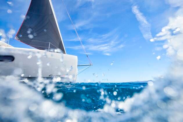 Behind a wave a cruising catamaran under sails by a sunny day. Canet-en-Roussillon, Occitanie, France ,editorial use only CR_CHLA200203-250856-01