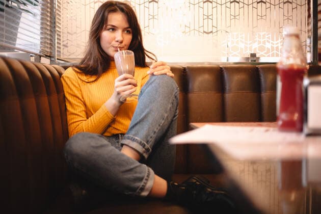 Thoughtful teenage girl drinking chocolate milkshake in restaurant ,model released, Symbolfoto CR_DMBE200203-287455-01