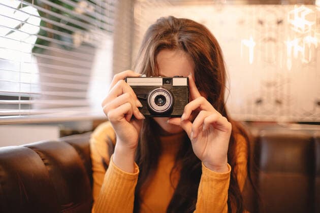 Teenage girl photographing with vintage camera while sitting in cafe ,model released, Symbolfoto CR_DMBE200203-287476-01