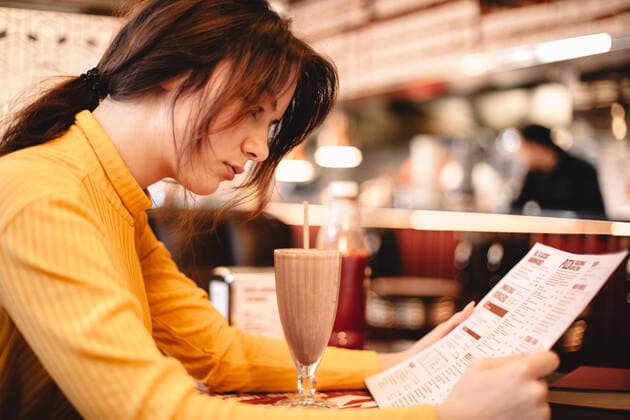 Teenage girl reading menu while sitting in restaurant ,model released, Symbolfoto CR_DMBE200203-287539-01