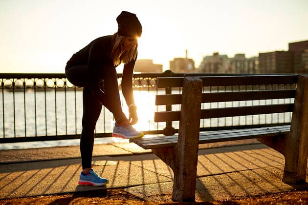 A backlit athletic woman ties her sneaker on a park bench. Boston, MA, United States ,model released, Symbolfoto CR_SDXQ200206D-294073-01
