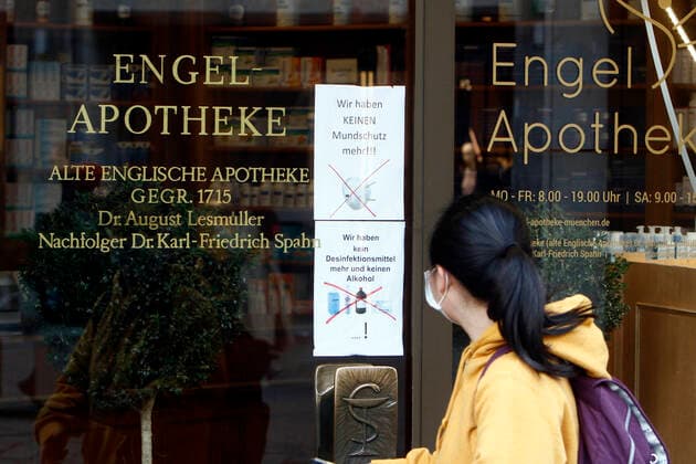Eine Touristin aus Asien passiert mit Atemschutzmaske eine Apotheke in der Innenstadt München, die wegen Ausverkaufs weder Desinfektionsmittel, noch Atemschutzmasken und Alkohol anbieten kann, München, Bayern, Deutschland