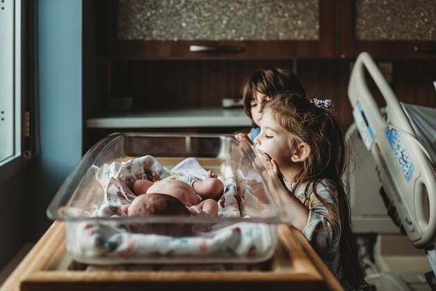 IMAGO Creative: Dichotomien, Generationen Sisters looking at newborn brother in hospital bassinet San Diego, CA, United States ,model released, Symbolfoto CR_KESM200220-261101-01