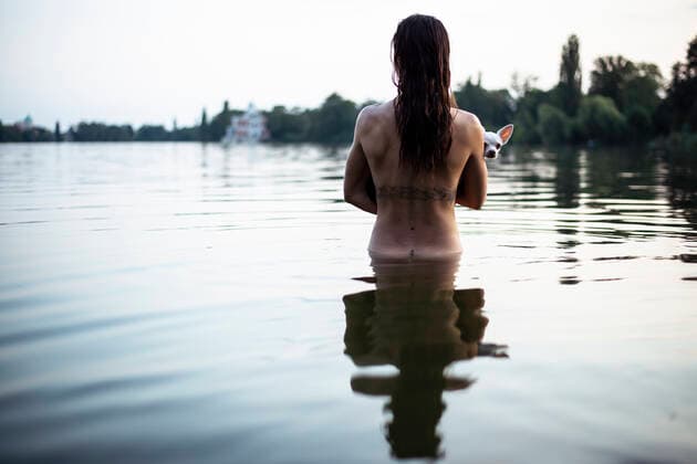 back view of strong woman holding small dog in natural berlin lake ,model released, Symbolfoto CR_PIDODS200220B-239379-01