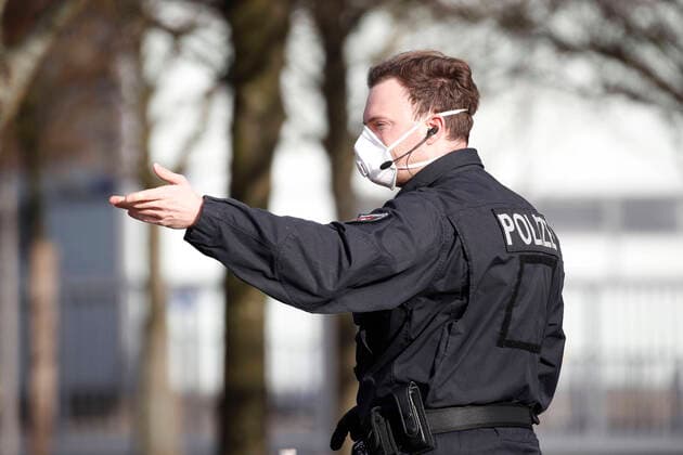 18.03.2020, Messegelaende, Halle 13, Hannover, Laatzen, Kontrollstelle fuer Corona Verdachtsfaelle, im Bild Polizist mit Schutzmaske gibt Zeichen Corona Drive-In