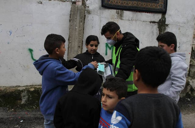 (200320) -- TRIPOLI, March 20, 2020 (Xinhua) -- A volunteer distributes masks to children as a precautionary measure against the COVID-19 epidemic at a community in Tripoli, Lebanon, March 20, 2020. Lebanon s Health Ministry announced on Friday that the number of COVID-19 cases in the country has increased to 163, the National News Agency reported. (Photo by Khalid Xinhua) LEBANON-TRIPOLI-COVID-19-VOLUNTEER 