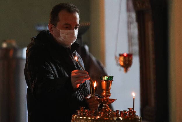 MOSCOW, RUSSIA - MARCH 20, 2020: A believer in a medical mask during an evening service at the Vysokopetrovsky Monastery. Starting from March 18, monks conduct a religious procession and spray holy water after the evening service at the monastery amid the coronavirus pandemic. Sergei Bobylev TASS  TS0D2EE4