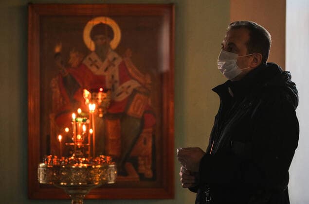 MOSCOW, RUSSIA - MARCH 20, 2020: A believer in a medical mask during an evening service at the Vysokopetrovsky Monastery. Starting from March 18, monks conduct a religious procession and spray holy water after the evening service at the monastery amid the coronavirus pandemic. Sergei Bobylev TASS  TS0D2EE9
