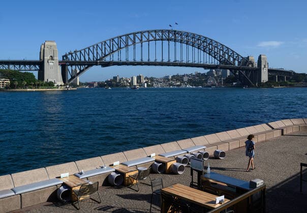 CORONAVIRUS AUSTRALIA, A lone woman walks through a quiet Opera Bar in front of the Sydney Harbour Bridge, Sydney, Saturday, March 21, 2020. Sydney is seeing a dramatic reduction in people on the streets as people are asked to enact social distancing and self isolation in order to prevent the spread of Covid-19. ( NO ARCHIVING, EDITORIAL USE ONLY, NO USE IN BOOKS WITHOUT CONSENT SYDNEY NSW AUSTRALIA  Copyright: xJAMESxGOURLEYx 20200321001458535919