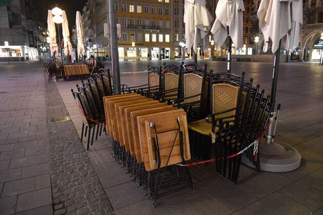 Themenbild Corona Pandemie:Bayern beschliesst Ausgangsbeschraenkung. Menschenleerer Marienplatz , Fussgaengerzone in Muenchen am spaeten Abend vor Verhaengung der Ausgangsbeschraenkung am 20.03.2020. Tische und Stuehle der Restaurants und Lokale sind zusammengeklappt und angekettet. Vereinzelt sind noch Menschen unterwegs.