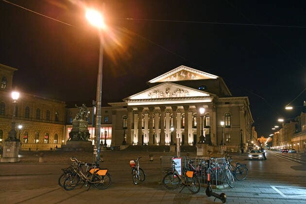 Themenbild Corona Pandemie:Bayern beschliesst Ausgangsbeschraenkung. Max Joseph Platz mit Blick auf das Nationaltheater,Oper n Muenchen am spaeten Abend vor Verhaengung der Ausgangsbeschraenkung am 20.03.2020 Gang vereinzelt sind noch Fussgaenger,Menschen unterwegs, Im Vordergrund stehen absgestelte Leihfahhraeder.