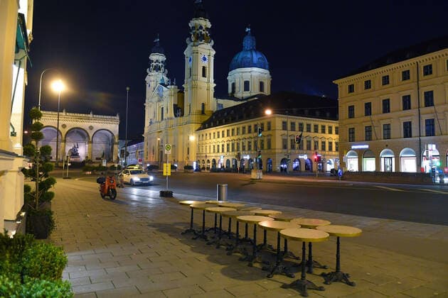 Themenbild Corona Pandemie:Bayern beschliesst Ausgangsbeschraenkung. Blick auf den Odeonsplatz mit Feldherrnhalle und Theatinerkirche in Muenchen. Im Vordergrund stehen die Bistrotische des Cafes Tambosi aneinandergekettet am spaeten Abend vor Verhaengung der Ausgangsbeschraenkung am 20.03.2020. Wenige Taxis stehen am Strassenrand.