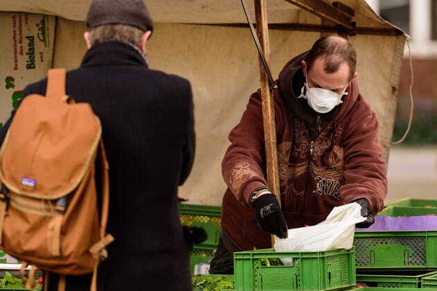 March 21, 2020: A market trader with a breathing mask serves his customers at the weekly market on Berlin s Winterfeldplatz. The Governing Mayor of Berlin, Michael Mueller (SPD), prepares restricting residents movements to contain the deadly coronavirus pandemic. Public venues such as bars, clubs, museums, cinemas, schools, daycare centers and universities have already closed. Many businesses are resorting to home office work for their employees. And travel across the border to most neighbouring countries is severely restricted. - ZUMAs172 20200321_zap_s172_021 Copyright: xJanxScheunertx