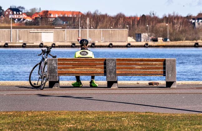 En cyklist slapper af alene paa en baenk ved havnefronten i Aalborg, loerdag den 21. marts 2020. Langs hele havnen i Aalborg var der god afstand mellem de mange folk der var ude og nyde vejret. Paa grund af COVID-19 er befolkningen blevet bedt om saa vidt muligt at holde sig indendoers og udendoers aktiviteter i det flotte foraarsvejr skal foregaa med god afstand.. , Aalborg Jylland Denmark Copyright: HenningxBagger HenningxBaggerx COP110 spdk20200321-131500-L