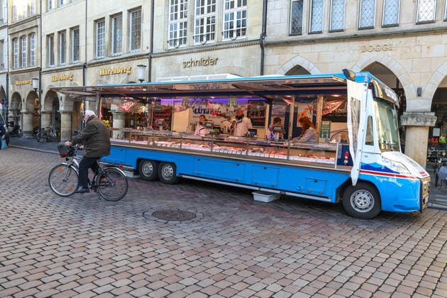 DEU, Deutschland, Nordrhein-Westfalen, Münster, 21.03.2020: Anfang des 20. Jahrhunderts war der Wochenmarkt Münster vom Prinzipalmarkt auf den Domplatz umgezogen. Wegen der Corona Ansteckungsgefahr wurde der Wochenmarkt entzerrt, damit zwischen Ständen Freiflächen für wartende Kunden entstehen. Einige Marktstände stehen deshalb am Prinzipalmarkt und am Michaelisplatz werden Stände aufgebaut. Abstandsregeln wurden von den Kunden beachtet.