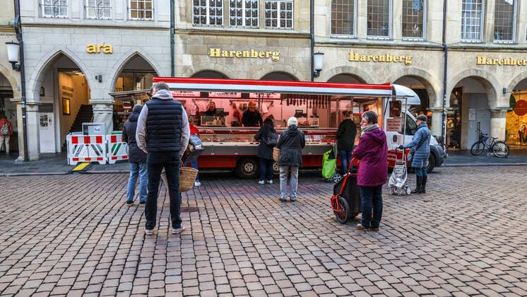 DEU, Deutschland, Nordrhein-Westfalen, Münster, 21.03.2020: Anfang des 20. Jahrhunderts war der Wochenmarkt Münster vom Prinzipalmarkt auf den Domplatz umgezogen. Wegen der Corona Ansteckungsgefahr wurde der Wochenmarkt entzerrt, damit zwischen Ständen Freiflächen für wartende Kunden entstehen. Einige Marktstände stehen deshalb am Prinzipalmarkt und am Michaelisplatz werden Stände aufgebaut. Abstandsregeln wurden von den Kunden beachtet.