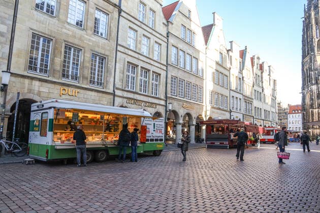 DEU, Deutschland, Nordrhein-Westfalen, Münster, 21.03.2020: Anfang des 20. Jahrhunderts war der Wochenmarkt Münster vom Prinzipalmarkt auf den Domplatz umgezogen. Wegen der Corona Ansteckungsgefahr wurde der Wochenmarkt entzerrt, damit zwischen Ständen Freiflächen für wartende Kunden entstehen. Einige Marktstände stehen deshalb am Prinzipalmarkt und am Michaelisplatz werden Stände aufgebaut. Abstandsregeln wurden von den Kunden beachtet.