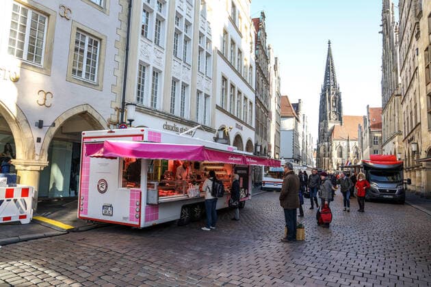 DEU, Deutschland, Nordrhein-Westfalen, Münster, 21.03.2020: Anfang des 20. Jahrhunderts war der Wochenmarkt Münster vom Prinzipalmarkt auf den Domplatz umgezogen. Wegen der Corona Ansteckungsgefahr wurde der Wochenmarkt entzerrt, damit zwischen Ständen Freiflächen für wartende Kunden entstehen. Einige Marktstände stehen deshalb am Prinzipalmarkt und am Michaelisplatz werden Stände aufgebaut. Abstandsregeln wurden von den Kunden beachtet.