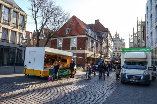 DEU, Deutschland, Nordrhein-Westfalen, Münster, 21.03.2020: Anfang des 20. Jahrhunderts war der Wochenmarkt Münster vom Prinzipalmarkt auf den Domplatz umgezogen. Wegen der Corona Ansteckungsgefahr wurde der Wochenmarkt entzerrt, damit zwischen Ständen Freiflächen für wartende Kunden entstehen. Einige Marktstände stehen deshalb am Prinzipalmarkt und am Michaelisplatz werden Stände aufgebaut. Abstandsregeln wurden von den Kunden beachtet.