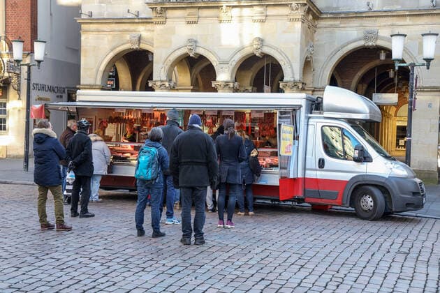 DEU, Deutschland, Nordrhein-Westfalen, Münster, 21.03.2020: Anfang des 20. Jahrhunderts war der Wochenmarkt Münster vom Prinzipalmarkt auf den Domplatz umgezogen. Wegen der Corona Ansteckungsgefahr wurde der Wochenmarkt entzerrt, damit zwischen Ständen Freiflächen für wartende Kunden entstehen. Einige Marktstände stehen deshalb am Prinzipalmarkt und am Michaelisplatz werden Stände aufgebaut. Abstandsregeln wurden von den Kunden beachtet.