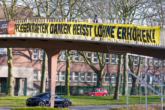Dortmund, 21.3.2020: Im Zusammenhang mit der Personalbelastung in der Pflege während der Coronakrise hängt ein Banner mit der Forderung zur Lohnerhöhung für Pflegekräfte an einer Fussgängerbrücke über dem Rheinlanddamm (Bundesstrasse 1) im Stadtbereich von Dortmund.