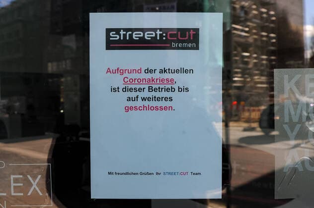 Zur Eindämmung des Coronavirus wurden Geschäftsschließungen angeordnet und werden Ausgangssperren diskutiert, das Foto zeigt ein Hinweisschild, Aushang im Fenster eines Geschäftes, eines Friseursalons, eines Frisörs, Aufschrift: Aufgrund der aktuellen Coronakriese (Coronakrise) ist dieser Betrieb bis auf weiteres geschlossen, 21.03.2020, Bremen (Deutschland), News, Feature, Coronavirus Bremen