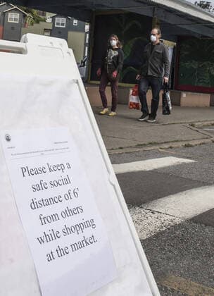 A sign asks shoppers at Farmers Market on Alemany Street to practice social distancing while waiting in line for produce in San Francisco on Saturday, March 21, 2020. All of California is ordered to shelter in place.  SXP2020032107 TERRYxSCHMITT