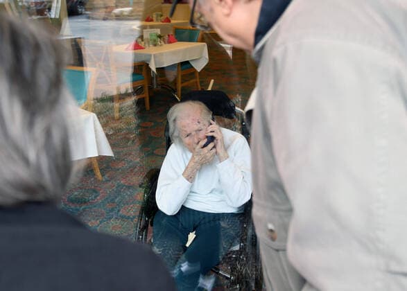 Wilma Grove uses a cell phone to talk to her children, Judy Kekich and Ed Grove during their visit to Delmar Gardens on the Green in Ballwin, Missouri on March 21, 2020. The family has been forced to visit their 100 year-old mother every day from the outside due to Coronavirus concerns. Missouri s known cases of COVID-19, is at 73 including three deaths.  SLP2020032103 BILLxGREENBLATT