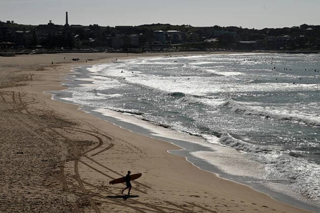 BONDI BEACH CORONAVIRUS CLOSURE, A surfers makes his way to the water at a closed at Bondi Beach in Sydney, Sunday, March 22, 2020. Beachgoers drew condemnation on Friday when tens of thousands of people flouted social distancing rules, which have been put in place in an effort to limit the spread of COVID-19. ( NO ARCHIVING, EDITORIAL USE ONLY, NO USE IN BOOKS WITHOUT CONSENT SYDNEY NSW AUSTRALIA  Copyright: xJOELxCARRETTx 20200322001458673648