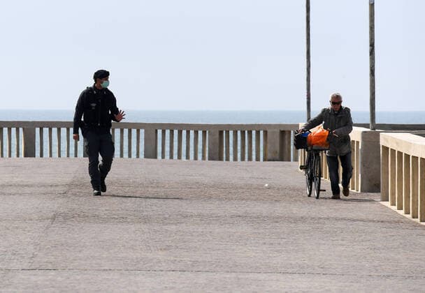 (200321) -- ROME, March 21, 2020 (Xinhua) -- A policeman talks to a man who enters a forbidden zone in Ostia, Rome, Italy, March 21, 2020. Italy reported 6,557 new cases of coronavirus on Saturday, raising the total to 53,578 since the pandemic first broke out in its north on Feb. 21, according to the latest data provided by the Civil Protection Department managing the COVID-19 emergency. (Photo by Elisa Lingria Xinhua) ITALY-ROME-OSTIA-COVID-19-CASES 