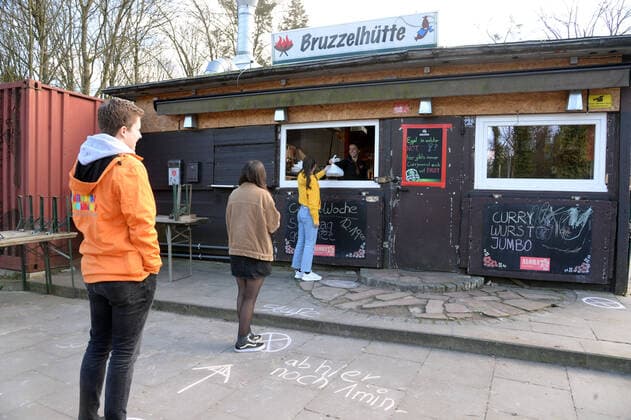 Hamburg, der 21.03.2020 Harburgs Kult-Currywurst-Brater Stefan Labann setzt auf Kreativität um das Geschäft in seiner Bruzzelhütte an der Bremer Straße aufrechtzuerhalten. Unter dem Motto Corona-Woche hat er seinen Betrieb radikal umgestellt. Der Verkauf erfolgt nicht mehr wie sonst in der regelmäßig dicht gefülleten Bude, sondern ausschließlich am Fenster. Aus Abstandsmarkierungen macht er ein lustiges Kinderspiel mit springen, hüpfen, krabbeln. Und ZABS - Zum Auto Bring Service hat er ins Leben gerufen. Mitarbeiter bringen nach telefonischer Bestellung die Currywurst direkt ans Auto. Der Gastronom und die Bruzzelhütte sind bekannt durch Funk & Fernsehen. So fand nach einem Schärfewettessen dort der erste Rettungseinsatz statt (Bild berichtete) und unvergessene Momente wo er Joko&Class, sowie Dieter Bohlen im Supertalent