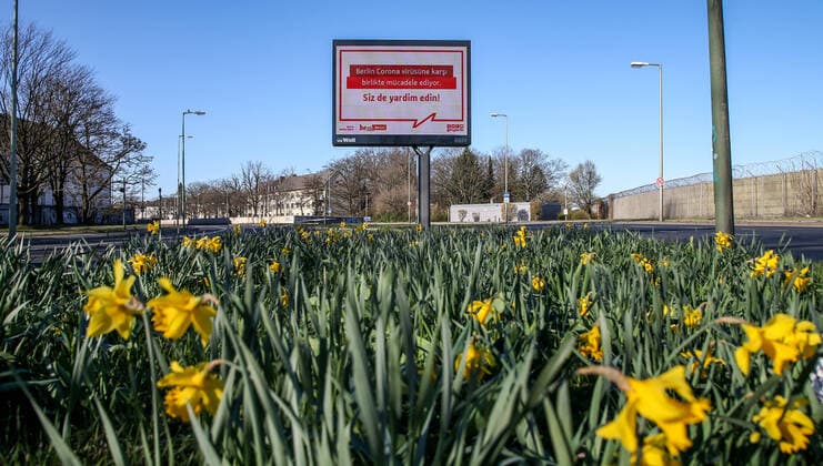 Coronavirus in Berlin Berlin, 22.03.2020, Wall Anzeigetafel zeigt Schriftzug der Berliner Regierung in türkischer Sprache: Berlin Corona virüsüne karsi birlikte mucadele ediyor. Siz de yardim edin!Reduce your social contacts to a minimum. Assist one another and show solidarity. Wegen des Coronavirus erinnert Berlin am Kurt-Schumacher-Damm an die Massnahmen zur Eindammung der Verbreitung des Coronavirus. Auf der Strasse ist kaum ein Auto zu erkennen. Gelbe Osterglocken bluehen am zweiten Fruehlingstag bei Sonnenschein und blauem Himmel. Berlin Berlin Deutschland Reinickendorf