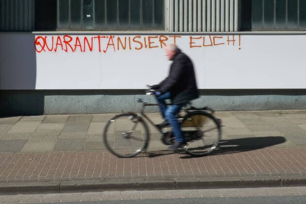 Zur Eindämmung des Coronavirus wurden Geschäftsschließungen angeordnet und werden Ausgangssperren diskutiert, das Foto zeigt einen Radfahrer, Fahrradfahrer vor einem Graffiti, Schriftzug an einem gebäude mit der Aufschrift: Quarantänisiert Euch, 22.03.2020, Bremen (Deutschland), News, Feature, Coronavirus Bremen