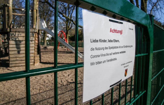 Coronavirus in Berlin Berlin, 22.03.2020, Sperrung Spielplatz am Tegler See. Schild zeigt Schriftzug: Achtung! Liebe Kinder, liebe Eltern, die Nutzung des Spielplatzes ist zur Eindaemmung des Corona-Virus bis auf weiteres verboten. Wir bitten um Verstaendnis. Ihr Strassen- und Gruenflaechenamt Reinickendorf. Hinter dem Zaun zeigen sich verlassene Spielgeraete. Berlin Berlin Deutschland Reinickendorf