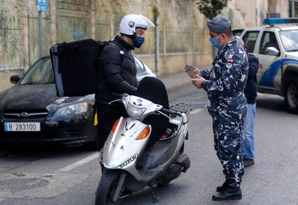(200322) -- BEIRUT, March 22, 2020 (Xinhua) -- A security forces member checks the identity document of a motorcyclist in Beirut, Lebanon, March 22, 2020. Lebanon s number of COVID-19 infected cases increased on Sunday by 18 to 248, the National News Agency reported. Lebanon deployed on Sunday security forces all over the country to prevent people from leaving their houses in an attempt to restrict the spread of COVID-19. (Photo by Bilal Jawich Xinhua) LEBANON-BEIRUT-COVID-19-MEASURES 