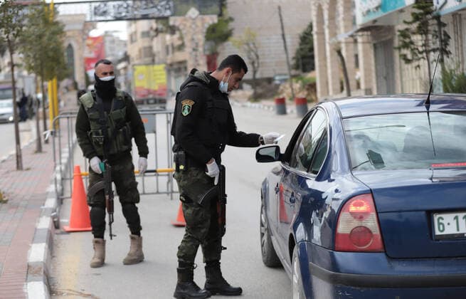 (200323) -- HEBRON, March 23, 2020 -- A Palestinian policeman works at a checkpoint at the entrance of the West Bank city of Hebron, March 23, 2020. Palestinian authorities on Sunday declared a 14-day lockdown on the West Bank as part of measures to combat the spread of coronavirus pandemic. Prime Minister Mohammed Ishtaye announced a ban on transportation and movement between the West Bank districts, urging citizens to stay at home. (Photo by Mamoun Wazwaz Xinhua) MIDEAST-HEBRON-COVID-19-MEASURES XiongxSihao 